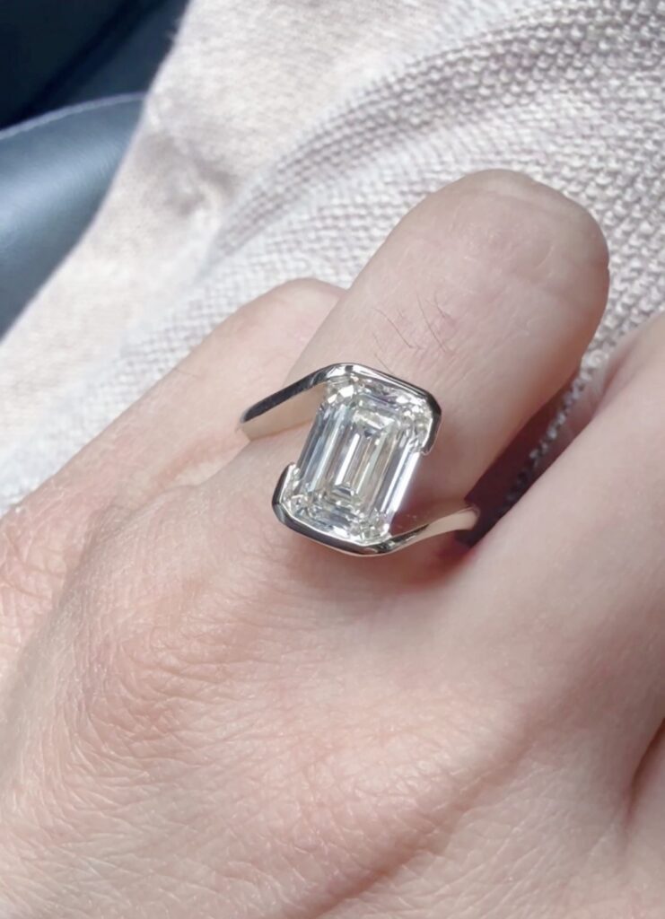 Emerald cut lab grown diamond engagement ring in bezel setting on hand by Haejin Jewelry Brooklyn