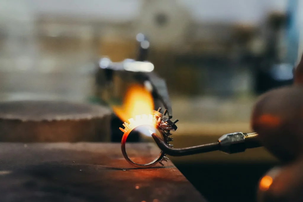 Jeweler soldering a solid gold engagement ring setting with a torch at Haejin Jewelry Brooklyn studio