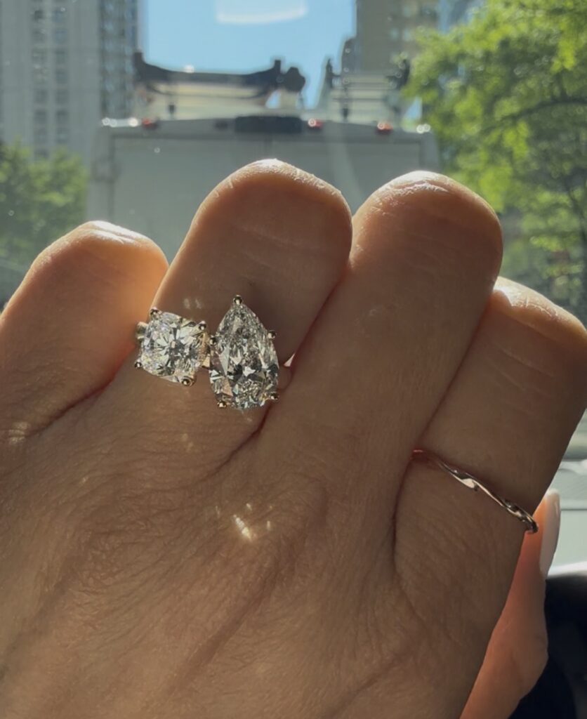 Toi et moi engagement ring with cushion and pear lab grown diamonds on hand in NYC sunlight by Haejin Jewelry